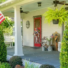 Classic southern American farmhouse front porch decorated for a summer 4th of July celebration. related to Country Chic Window Treatments: Elevating Your Porch with Beautiful Valances