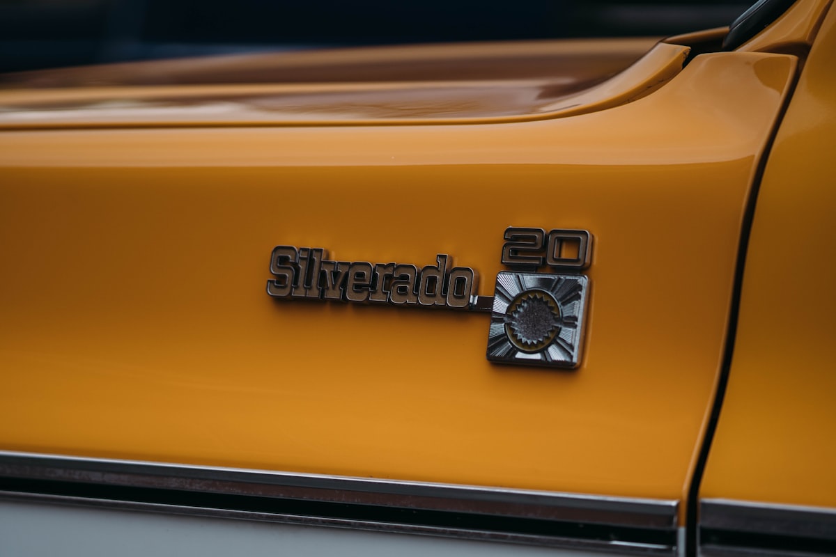 Close-up of a silver silverado 20 emblem on yellow truck. related to Protect Your Investment: The Ultimate Guide to Silverado Bed Liners