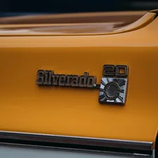 Close-up of a silver silverado 20 emblem on yellow truck. related to Protect Your Investment: The Ultimate Guide to Silverado Bed Liners