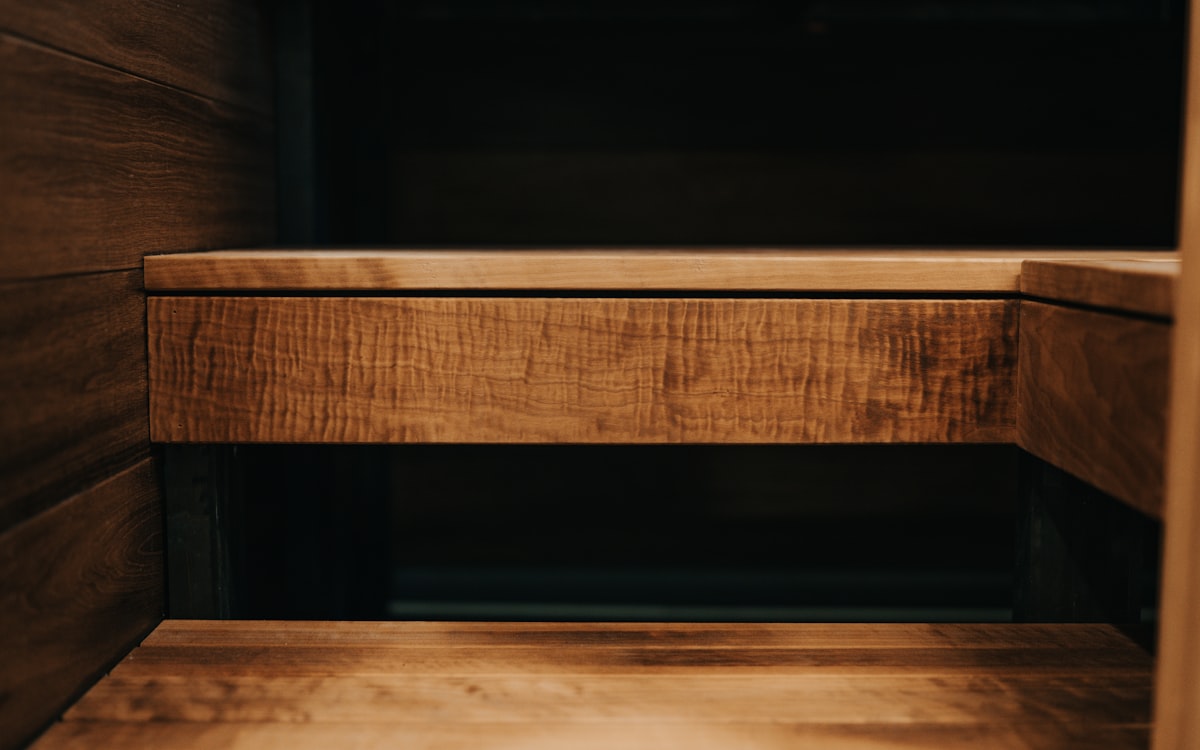 Close-up of wooden sauna bench with a rich, dark brown finish and visible wood grain texture. related to Corner Storage Bench Entryway