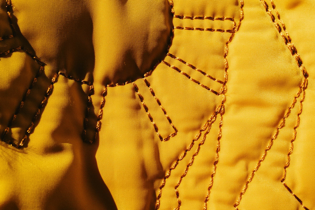 Close up of yellow fabric with stitched details. related to Luxurious Diamond Quilted Coverlets for a Regal Touch