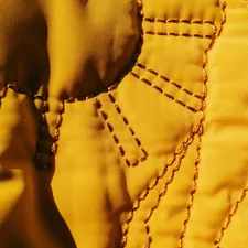 Close up of yellow fabric with stitched details. related to Luxurious Diamond Quilted Coverlets for a Regal Touch