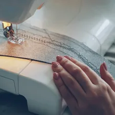 Close-up shot of working modern sewing machine, fabric and manicured female hand. Clothes manufacturing process concept. Light soft colours, beautiful stitches. related to Sewing Made Easy: Free Valance Patterns to Get You Started