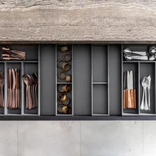 Copper and silver cutlery in an organized wooden kitchen drawer related to Elegant Storage Solutions: The Black Sideboard Table