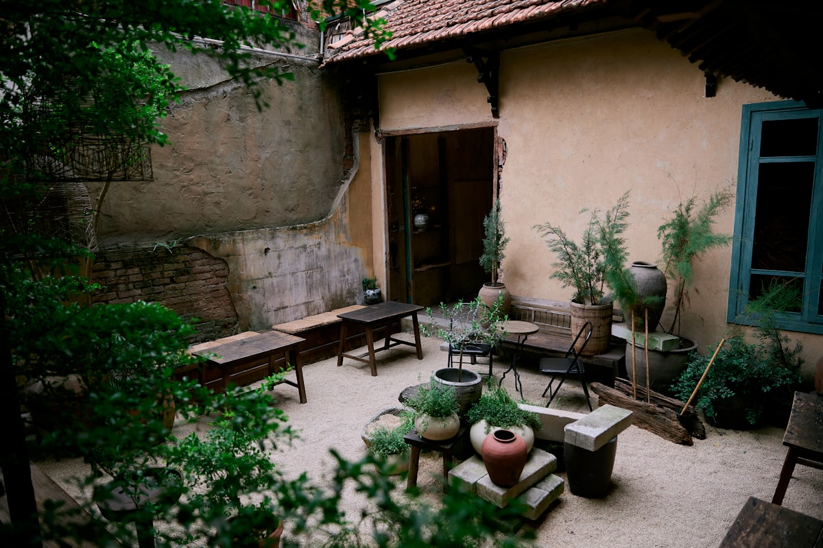 Courtyard with plants and wooden benches related to Spice Up Your Outdoor Space with Chimineas on Sale