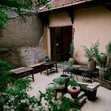 Courtyard with plants and wooden benches related to Spice Up Your Outdoor Space with Chimineas on Sale