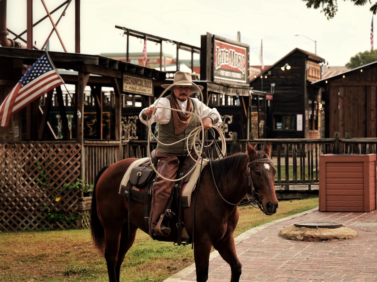 Cowboy on horseback holding a lasso in a western town related to Discover the Urban Cowboy Bed and Breakfast Experience