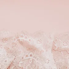Delicate white lace fabric on a pale pink background related to White Lace Shower Curtain with Valance