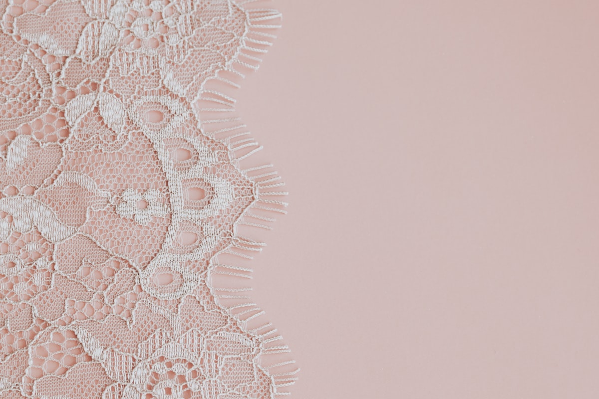 Delicate white lace fabric on a soft pink background. related to Elegant Bathroom Essentials: Lace Shower Curtains with Valance