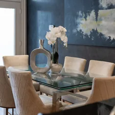 Elegant dining room with glass table and upholstered chairs. related to dining room sideboard decorating ideas