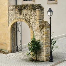 Elegant historic stone archway with an ornate wrought iron gate and a classic black street lamp on a cobblestone pavement. related to Revamping Your Home's Welcome: Outside Entryway Ideas