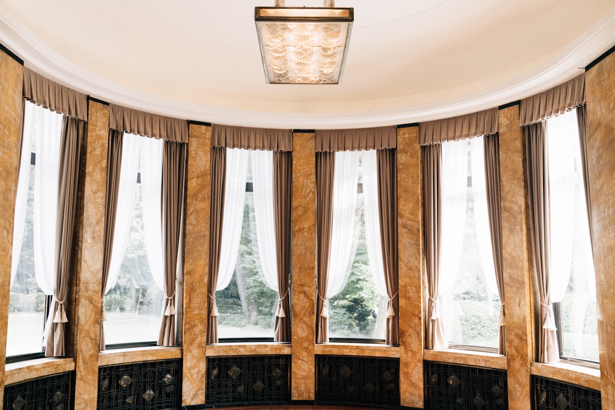 Elegant room with large windows and ornate columns related to Wood Valances for Windows: Enchanting Window Treatments