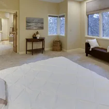 empty bed near open bathroom door related to Elevate Your Bedroom with an Ivory Coverlet for Your King-Size Bed