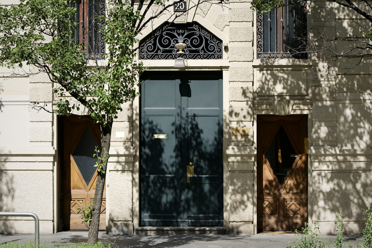 Entrance with three doors and tree shadows. related to Transforming Your Home's Entryway: The Power of the Perfect Door