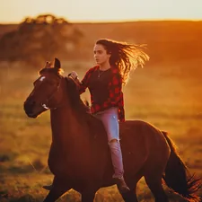 girl in blue denim jacket riding brown horse during daytime related to The Ultimate Guide to Stylish Horse Bedding for Equestrian Girls