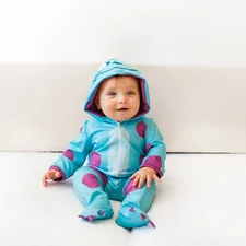 girl in pink hoodie and blue pants sitting on white floor related to Monster Baby Bedding: A Whimsical Way to Decorate Your Nursery