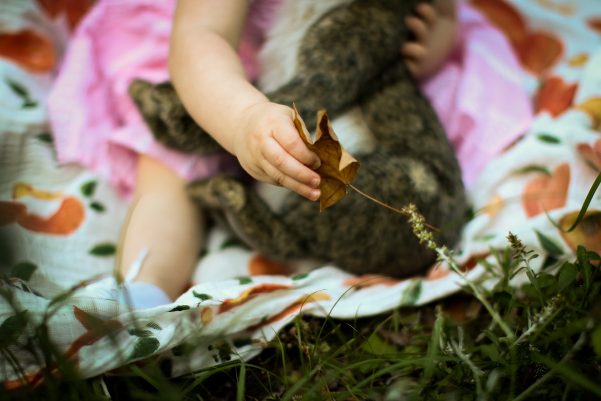 girl in white and pink dress lying on green grass field related to Enchanting Slumber: A Woodland Crib Bedding Guide