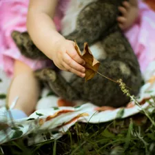 girl in white and pink dress lying on green grass field related to Enchanting Slumber: A Woodland Crib Bedding Guide