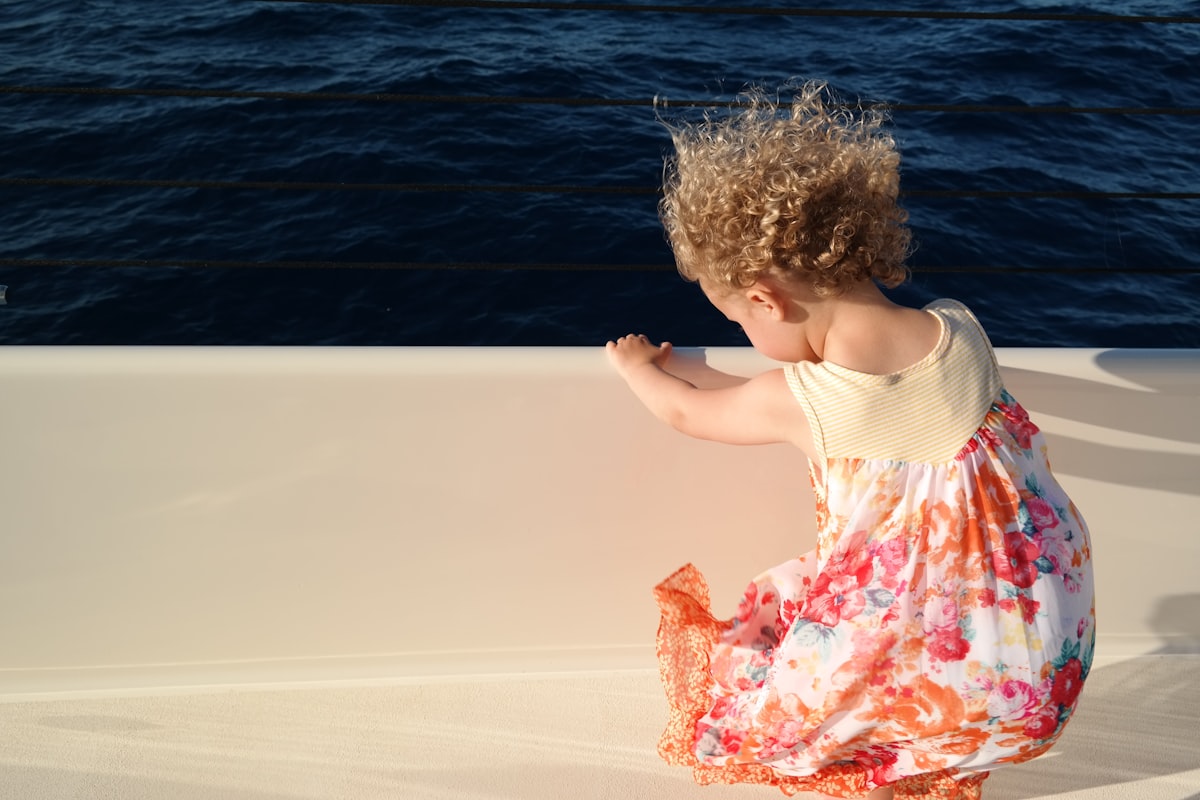 girl in white tank top and pink floral skirt standing on water during daytime related to Nautical Baby Girl Bedding: A Perfect Blend of Comfort and Style