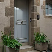 Gray door with potted plants on an old stone building. related to Elevating Your Entrance: Innovative Entryway Wall Decor Ideas
