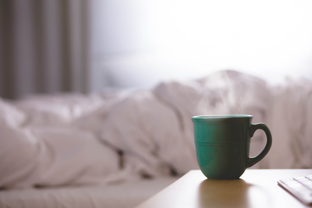 green ceramic mug on wooden desk related to Steep into Slumber: The Best Tea Before Bed