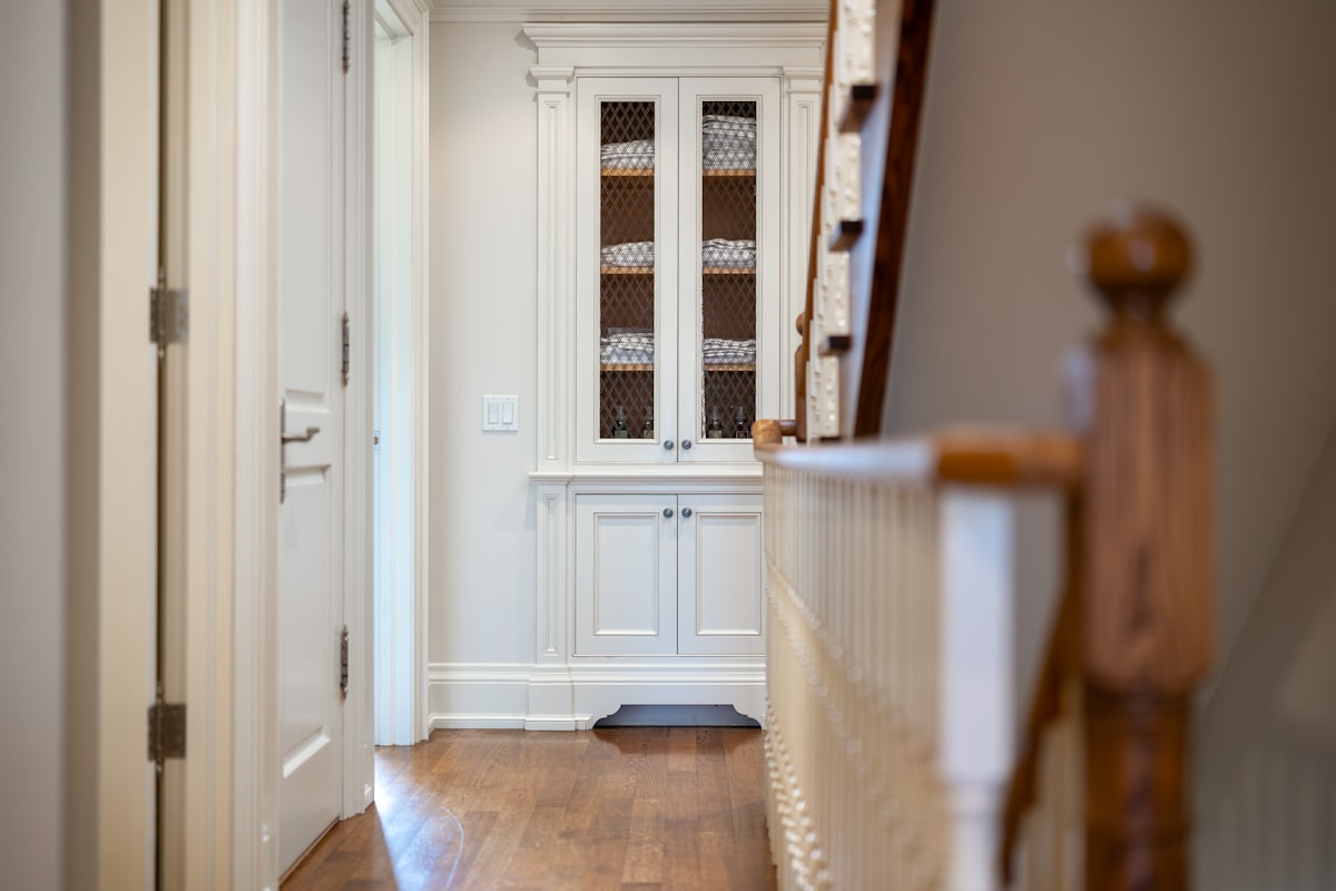 Hallway with white cabinet and wooden staircase related to Maximizing Space: The Power of a Small Entryway Bench