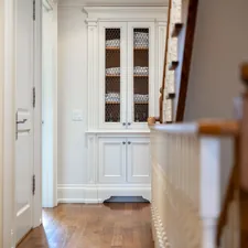 Hallway with white cabinet and wooden staircase related to Maximizing Space: The Power of a Small Entryway Bench
