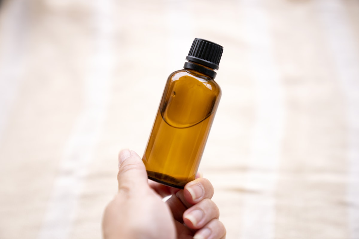 Hand holding amber glass bottle related to Don't Let Bed Bugs Bite: Effective Homemade Repellents