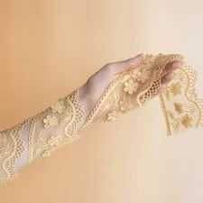 Hand holding delicate yellow lace fabric with floral pattern. related to Vintage Lace Valances: A Touch of Elegance for Your Home