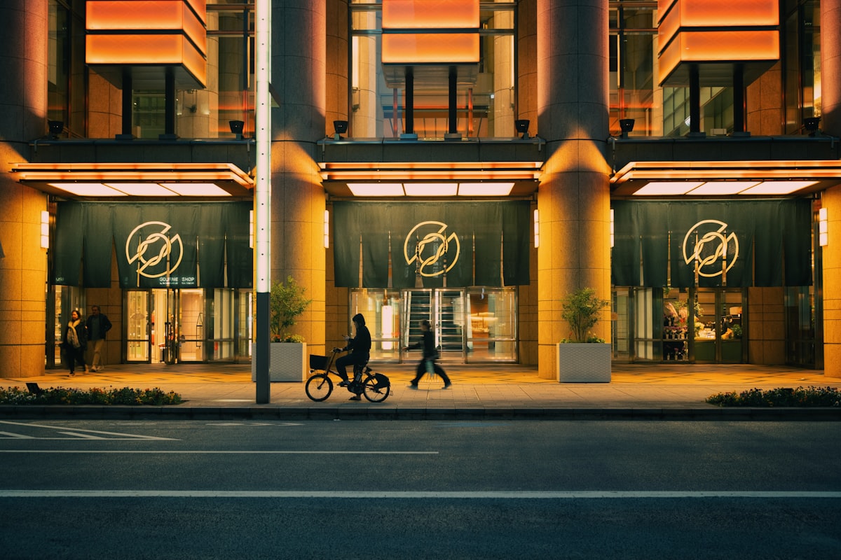 Illuminated modern building entrance with people on sidewalk at night. related to Elevate Your Home's Curb Appeal with Modern Entryway Lighting