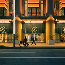 Illuminated modern building entrance with people on sidewalk at night. related to Elevate Your Home's Curb Appeal with Modern Entryway Lighting