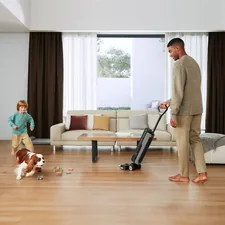 In a sunlit living room, a man uses a Dreame wet dry vacuum while his child and dog play nearby, creating a family-friendly cleaning moment. related to Elevate Your Home with Black and White Curtain Valance