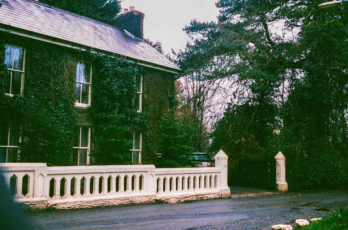 Ivy covered house with white stone fence and trees related to Discovering the Charm of Huron House Bed and Breakfast