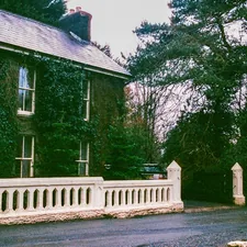 Ivy covered house with white stone fence and trees related to Discovering the Charm of Huron House Bed and Breakfast