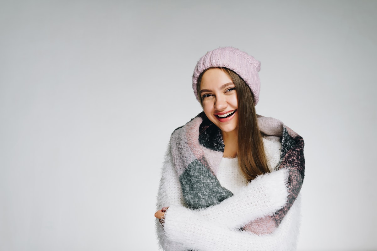 Joyful girl looks at the camera and smiles, winter and expectation of cold. Woman hugging herself from the cold. Winter background with people related to Pink Scarf Valance
