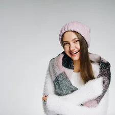 Joyful girl looks at the camera and smiles, winter and expectation of cold. Woman hugging herself from the cold. Winter background with people related to Pink Scarf Valance