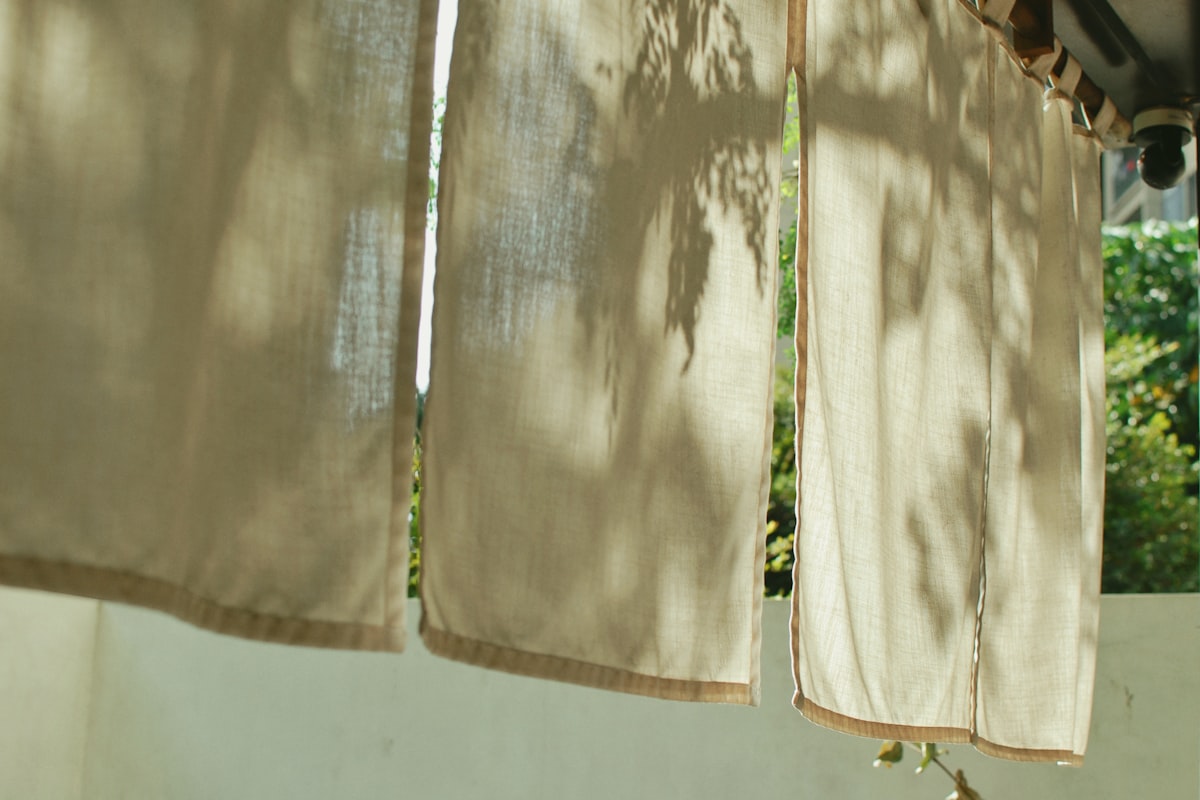 Light filtering through hanging linen curtains outdoors. related to How to Hang Curtains with Valance