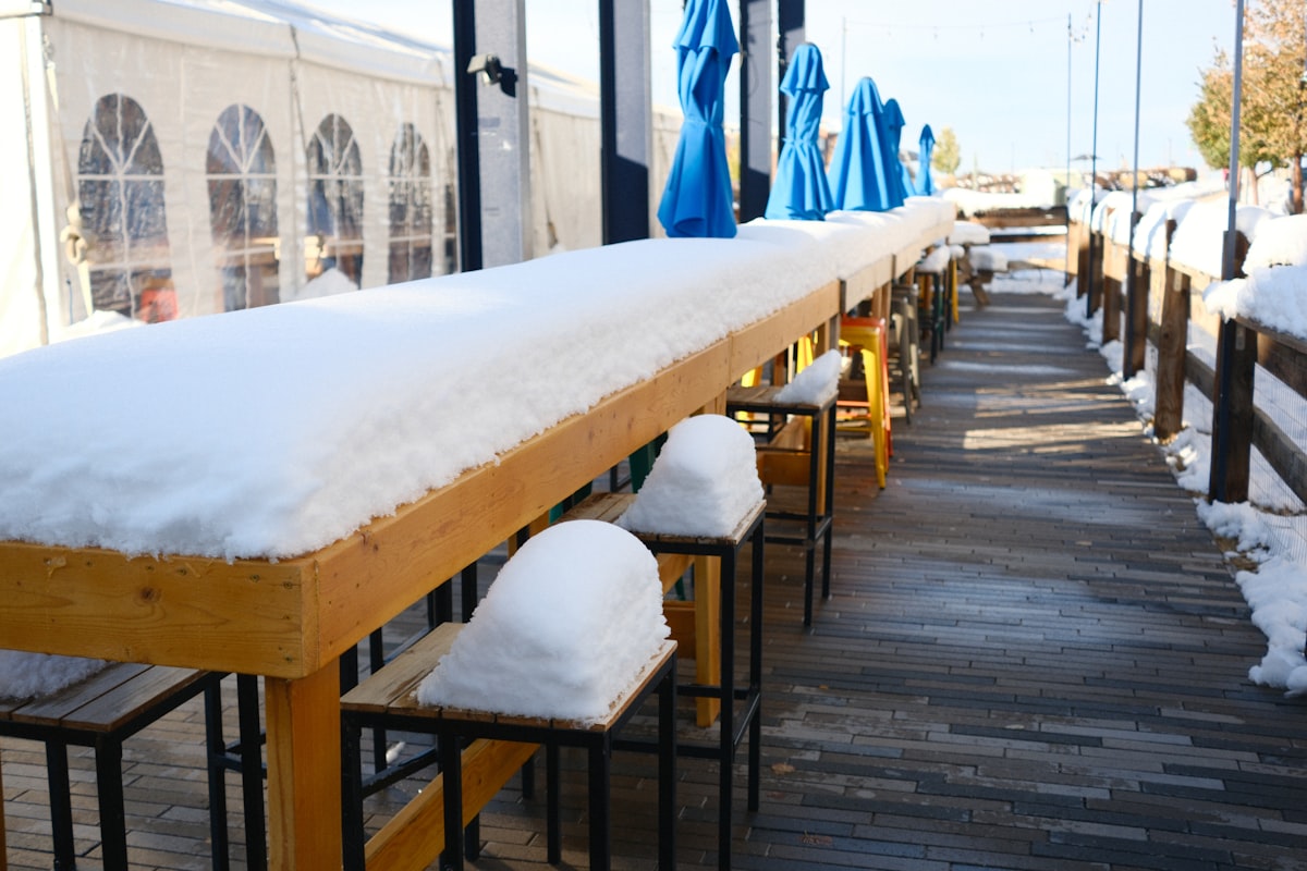 Long outdoor bar covered in snow with blue umbrellas. related to Warm Up Your Outdoor Space with a Majestic Ceramic Fireplace Chiminea