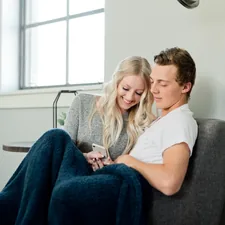 Lovebirds snuggle on the couch related to Cozying Up: The Benefits and History of Cast Iron Chimineas