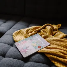 Magazine and rumpled blanket on sofa related to Stylish and Comfortable Baby Bedding Ideas