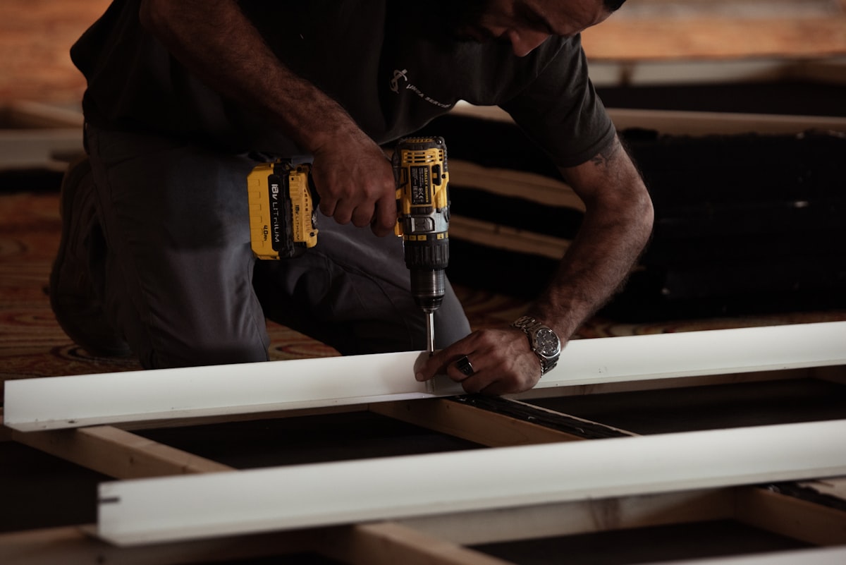man drilling on a wooden plank using a power drill related to Build a Valance