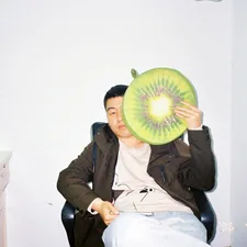 Man holding a kiwi fruit pillow in front of face related to Enhancing Comfort for Sitting in Bed