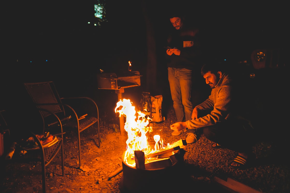 man in black jacket sitting beside fire pit during nighttime related to Warming Up to the Great Outdoors: The Ultimate Guide to Extra Large Cast Iron Chimineas