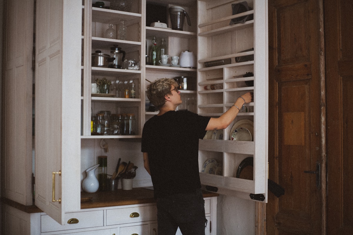 man standing near cabinet reaching plate related to Stylish Storage Solutions: Elevating Your Dining Space with a Red Sideboard Buffet