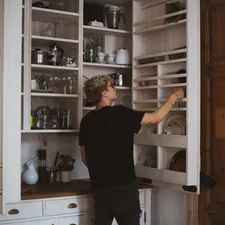 man standing near cabinet reaching plate related to Stylish Storage Solutions: Elevating Your Dining Space with a Red Sideboard Buffet