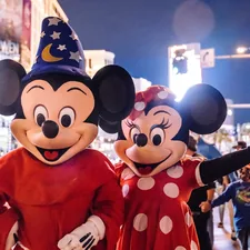 mickey mouse mascot standing near people in mickey mouse costume related to Magical Slumber: The Best Mickey Mouse Bedding for Kids