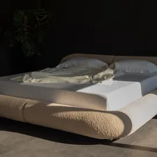 Modern bed with rounded headboard and white linens. related to Luxury Bedding Coverlets