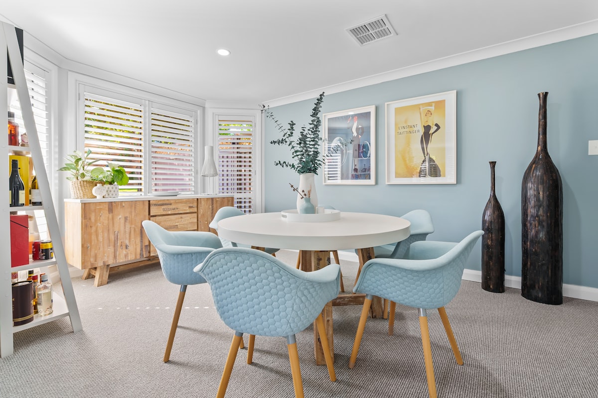 Modern dining room with round table and light blue chairs. related to Transform Your Space with the Zayley Twin Bookcase Bed