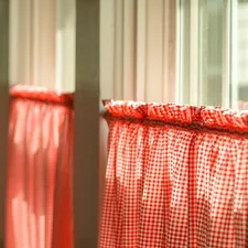 Morning sunlight shining through vintage kitchen windows of an old farm house with classic southern red checkered curtains. related to Kitchen Valance Patterns: Elevate Your Kitchen Decor