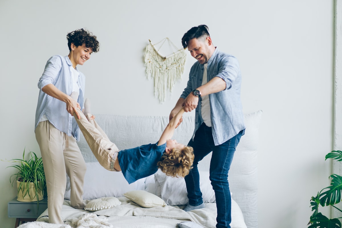 Mother father swinging child holding hands and feet then putting on bed at home related to Transform Your Home with Family Dollar Bedding: Affordable Comfort for Every Room